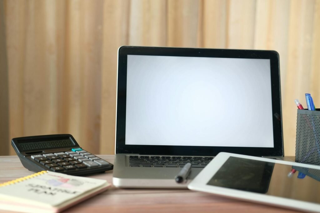 A new laptop on a clean desk beside a receipt, notebook, and pen.