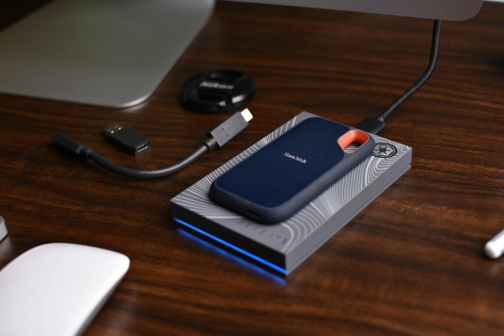 A laptop beside an external SSD, charging cable, and neatly arranged accessories.