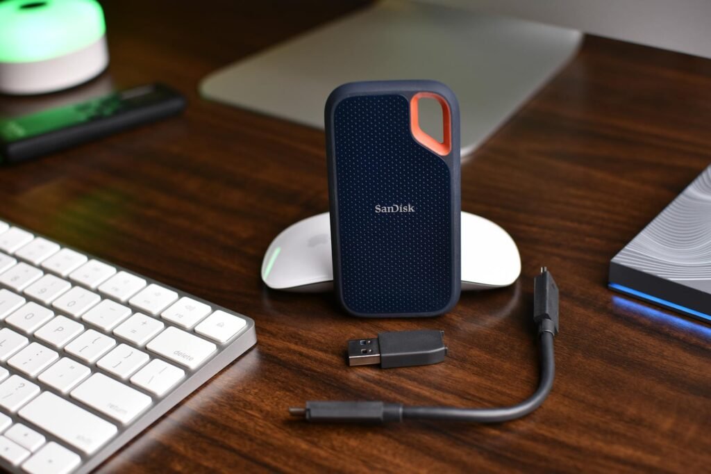 A home-office desk with a monitor, keyboard, and an external SSD used for backups.