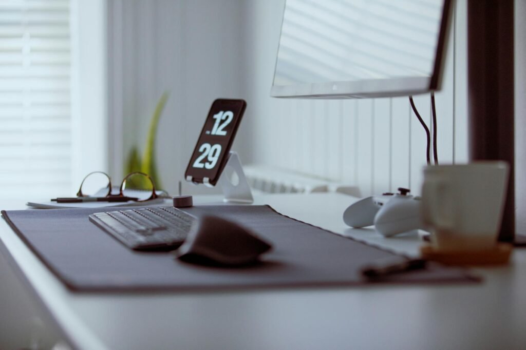 A close-up of a keyboard, mouse, notebook, and monitor arm on a tidy workstation