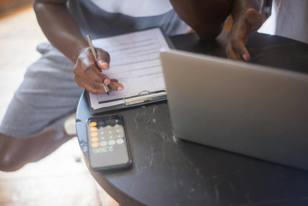 A laptop with settings open beside a handwritten checklist and calculator.