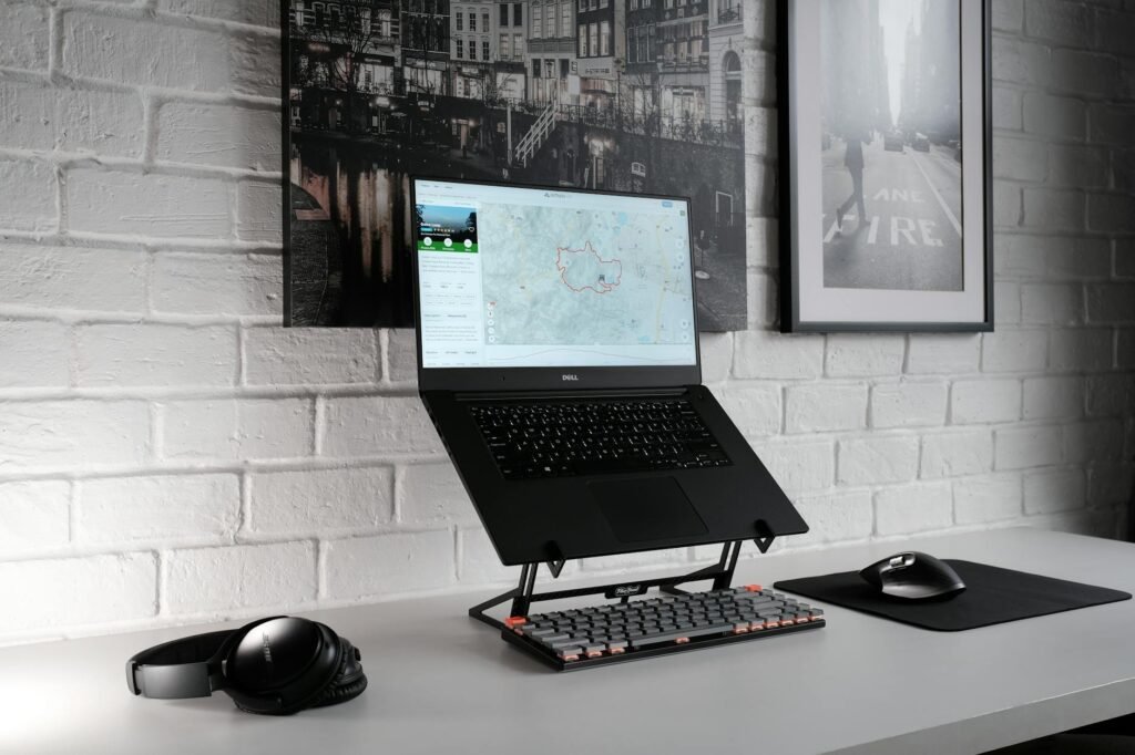 A laptop raised on a stand with an external keyboard and mouse on a desk