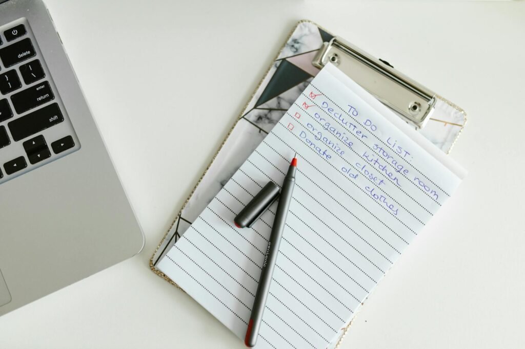 A new laptop on a desk beside a handwritten setup checklist and power adapter