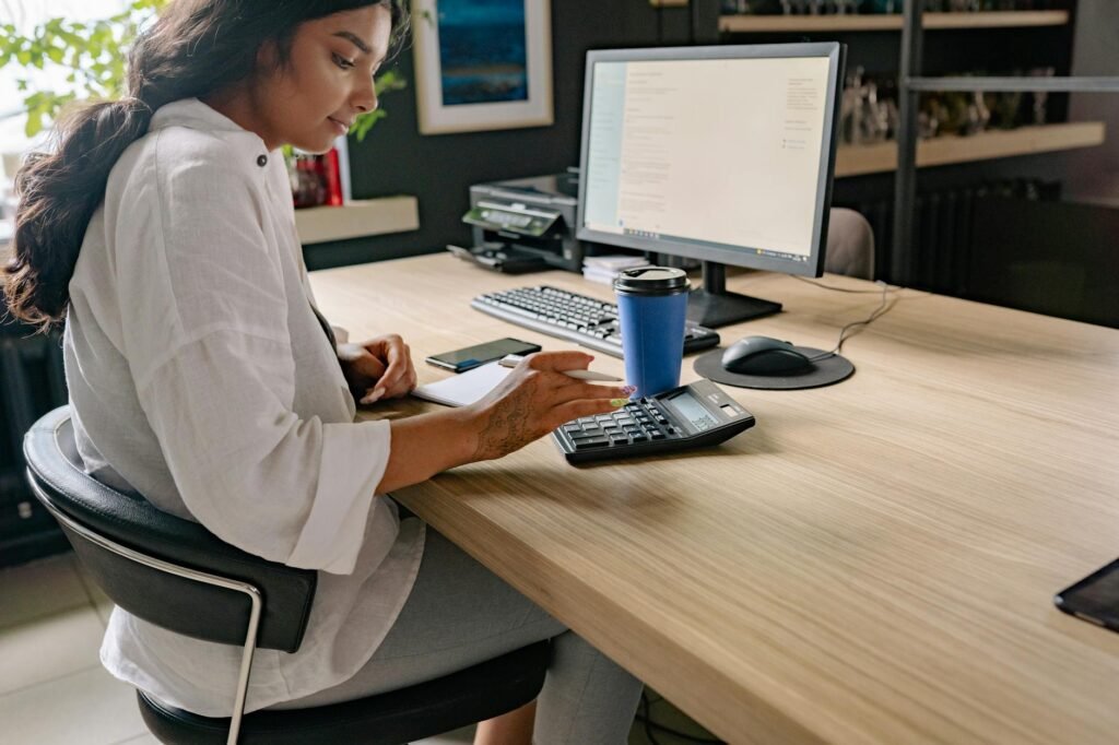 An organized desk with a monitor arm, keyboard, notebook, and calculator