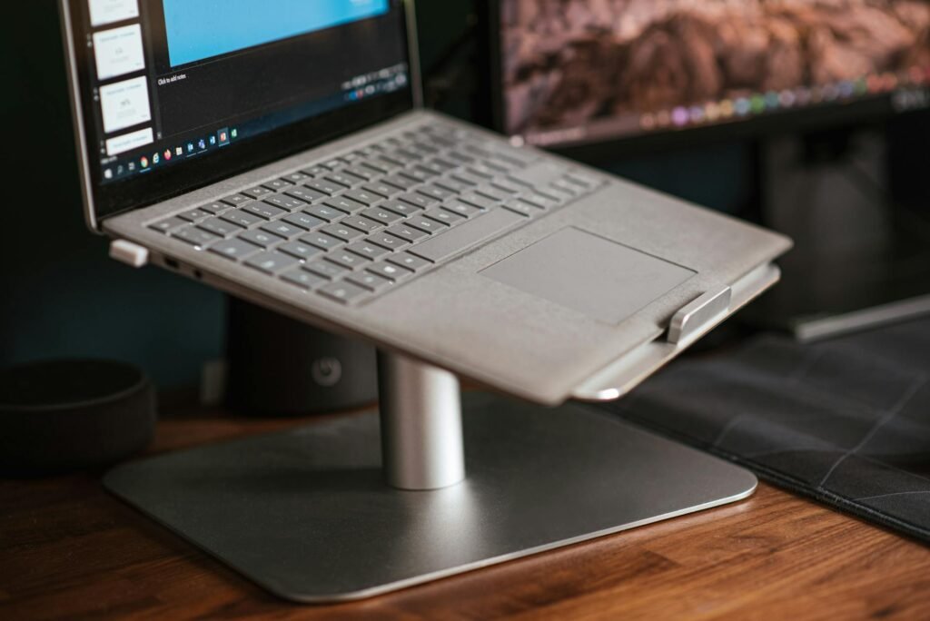 Laptop raised on a stand next to an external monitor at a similar height
